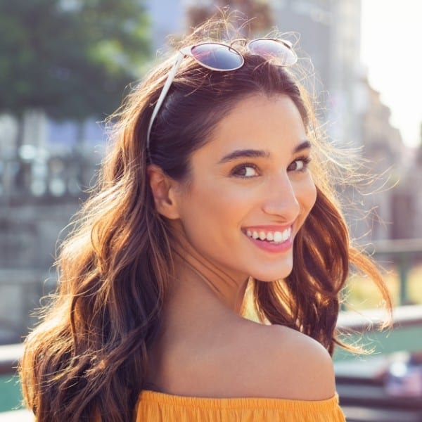 woman with sunglasses on head smiling outdoors